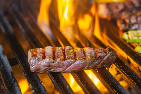 Tasty Beef steaks on the grill with fire flamesの写真素材