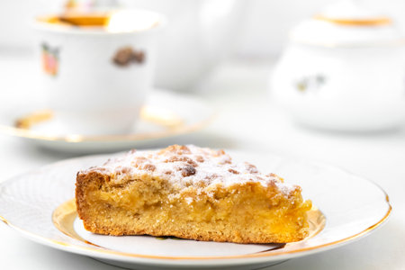Piece of delicious homemade pie on white plate, cup and teapot