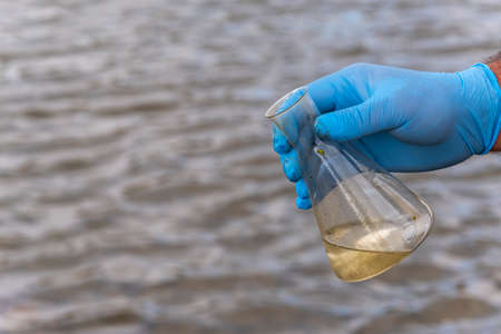 A water sample from the river. Hand in glove collects water in a test tube. ecology conceptの写真素材