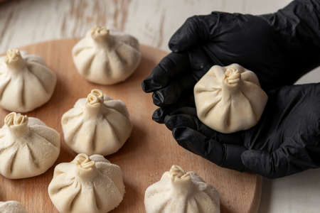 making khinkali for his family close-up. Unrecognizable cook preparing georgian traditional meal of dough and meat at kitchen. National cuisine, cooking process concept.frozenの写真素材