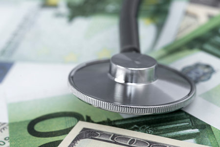 medical stethoscope in dollars and euro banknotesの写真素材