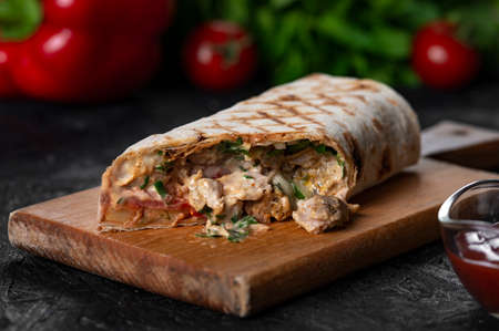 greek meat gyros with tzatziki sauce on black background.
