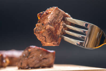 piece of meat on a fork, dark background