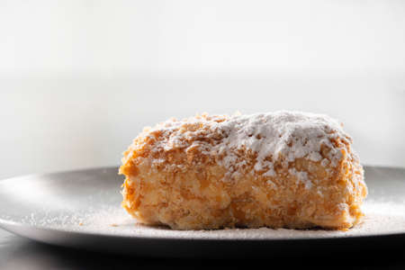 Napoleon cake with icing sugar on black background. Decorating napoleon cake with powdered sugar.