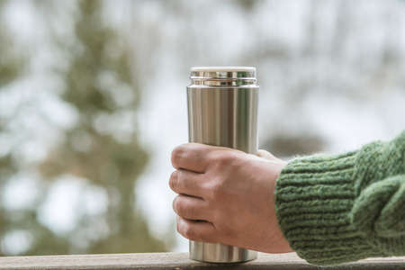 Man in the background of a winter forest in a flask bottle in handsの写真素材