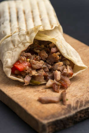 Doner kebab is on the cutting board. Shawarma with meat, onions, lettuce lies on a black background.の写真素材