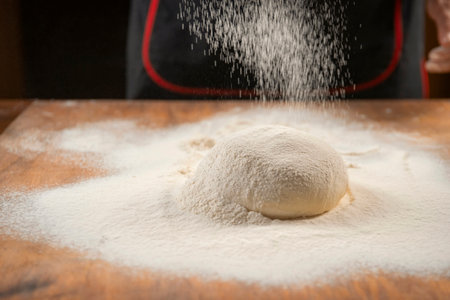 Baker pours flour for making pizza. Chef cooking dough to bake a cake on a wooden table. The process of making home baking. Cooking pasta, bread, spaghetti, khachapuri, food conceptの写真素材