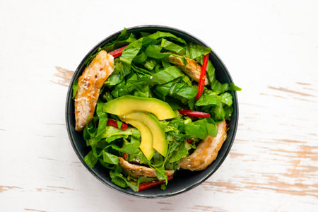 chicken salad with avocado in a black bowl. healthy foodの写真素材
