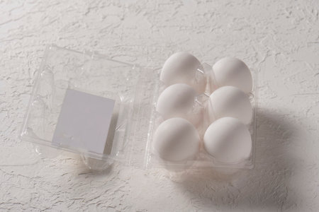 Open box with six whole white eggs on white background. Fresh organic chicken eggs in plastic pack...