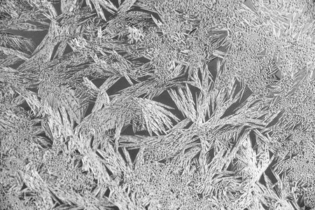 Texture of ice on the glass, icy surface of a frozen window, background, blue monochrome.