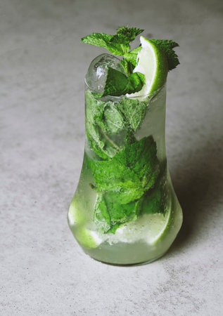 Mojito cocktail with lime and mint in highball glass on a gray stone background.の写真素材