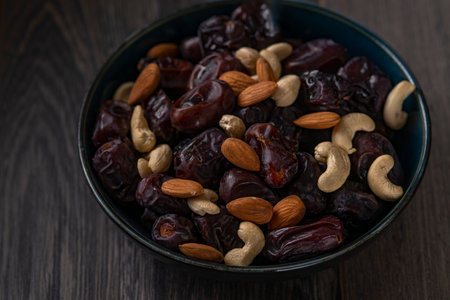 dates and nuts in a bowl on a dark backgroundの写真素材