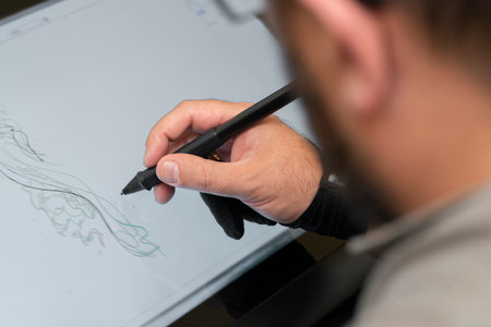 man holding a tablet and drawing with a pen in his handの写真素材