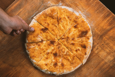 Persons take pieces of baked homemade cheese pie on wooden background. Bulgarian banitsa, Georgian khachapuri, Greek tiropitaの写真素材