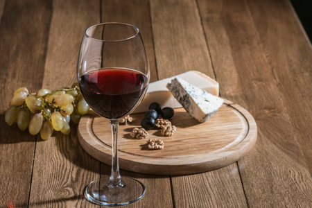 still life with red wine and cheese on a wooden tableの写真素材