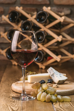 still life with red wine and cheese on a wooden tableの写真素材
