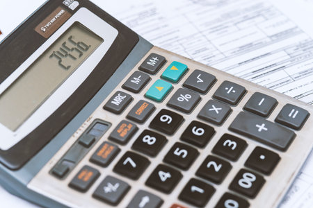 close up of a businessman's hand with a calculator and documentsの写真素材