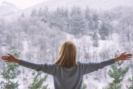 woman standing on balcony and looking at snowy mountains.の写真素材