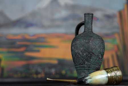 antique amphora with wine on wooden table.