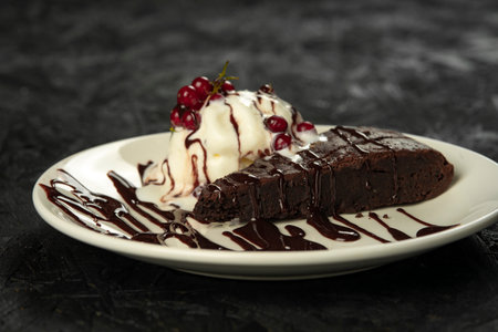 Chocolate brownie with ice cream and berries on a black backgroundの写真素材