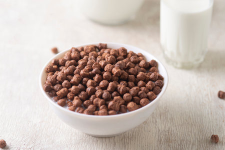 Bowl with chocolate corn balls and milk, on white wooden background.の写真素材