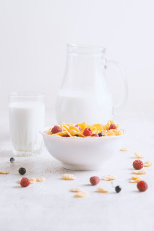 Healthy breakfast with cereal and blueberry and raspberry.Bowl with healthy cornflakes, milk and berries on white table.Tasty circle cornflakes.oatmeal with fruits. Diet concept.の写真素材