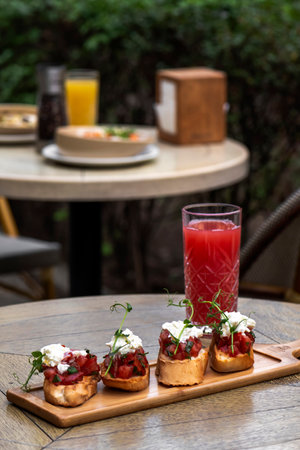 canape with tomato and feta cheese on a wooden table in a restaurant ÑŒBruschetta with tomatoes...
