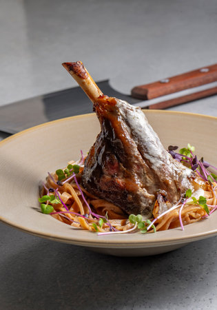 Lamb chop with noodles, sauce and mustard on a gray background