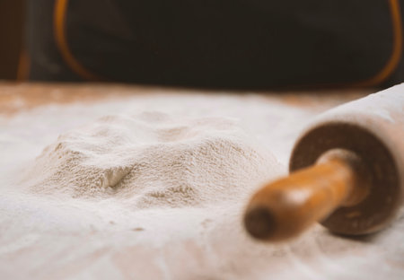 Close-up of a rolling pin and piles of flour with yolk on itの写真素材