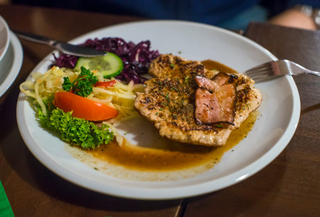 Grilled pork steak with fresh vegetable on white plate in restaurant.の写真素材