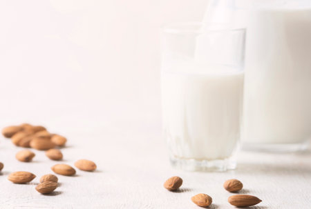 Alternative milk of almonds in a glass and glass jug on a wooden background. copy spaceの写真素材