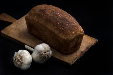 Dark bread and garlic on a black background.