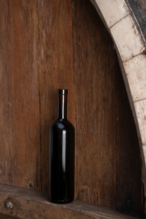 Bottle of red wine on a wooden background in a wineryの写真素材