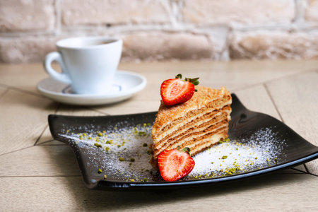 layer sponge cake with strawberries on a black plate on wooden backgroundの写真素材