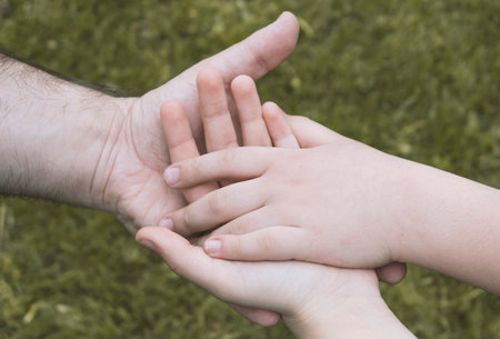 Father and son and daughter holding hands on green grass background. Close Up.の写真素材