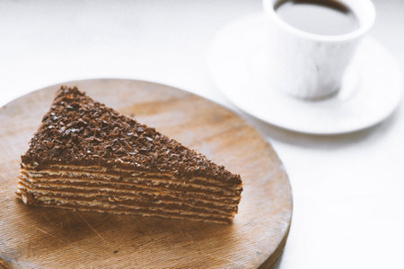 Piece of chocolate cake on a wooden plate with a cup of coffeeの写真素材