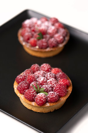 two raspberry tart on a black plate.の写真素材