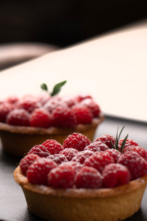 two raspberry tart on a black plate.の写真素材