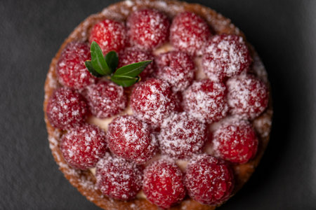 Raspberry tart on a black plate, top view, close-up