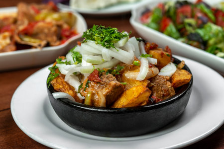 Beef stew with potatoes, carrots and herbs on black background with copy