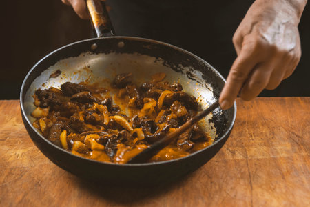 The cook prepares meat with vegetables and onion in a bowl. Oriental cuisine
