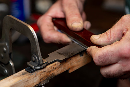 A close-up of a craftsman's hands as he creates a knife.