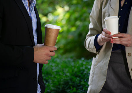 Close-up of business people holding paper cups of coffee. Focus on paper cup