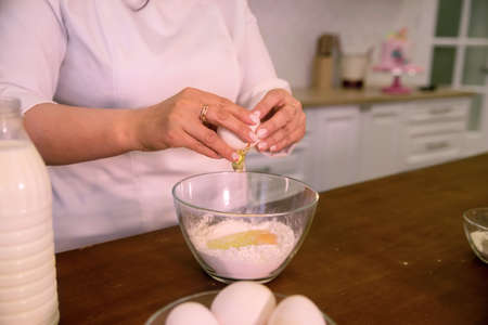 woman's hands prepare food, breaks an egg, baking, close-up