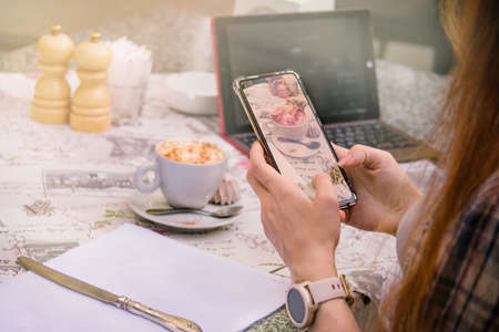 girl in a cafe photographs a cup of coffee on the phone in a cafe, hands close-up