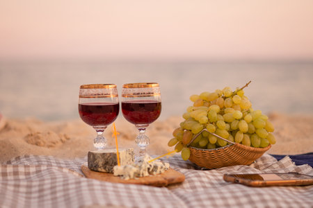 Two glasses of wine, cheese and fruits, close-up on the background of the sea. Joint trip to the sea. romantic date. copyspace.の写真素材