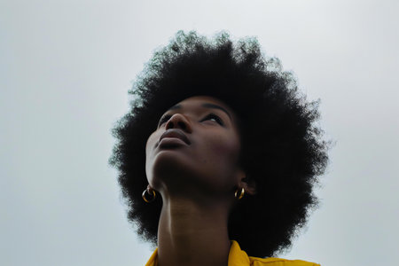 Young african american woman with afro hairstyle looking upの素材