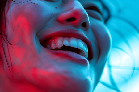 Close-up view of a beautiful young woman's mouth with glowing red teeth.の素材
