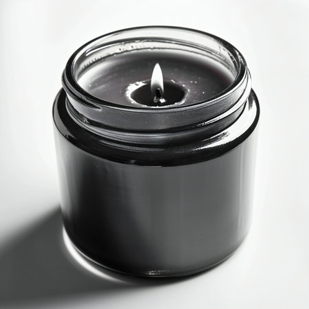 Candle in a black glass jar on a white background with shadowの素材
