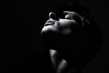 Studio portrait of a beautiful woman with closed eyes on a black backgroundの素材